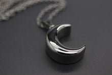 a silver necklace with a crescent design on it