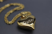 a gold necklace with a heart shaped object on a chain