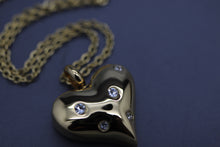 a gold heart shaped pendant with diamonds on a chain