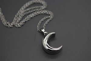 a silver necklace with a crescent on a chain