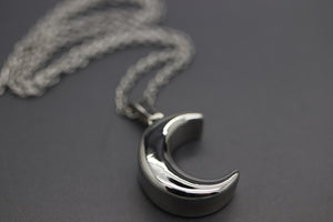 a silver necklace with a crescent on a chain