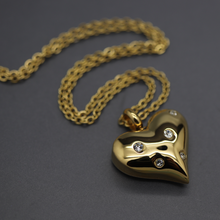 a gold heart shaped pendant with diamonds on a chain