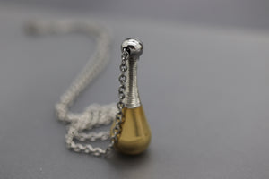 a small silver and gold object on a chain