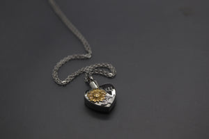 a heart shaped pendant with a flower on a chain