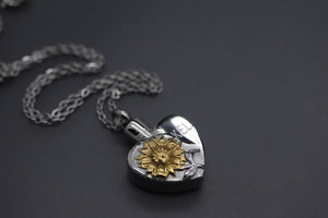 a heart shaped pendant with a flower on a chain