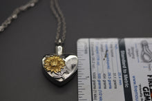 a heart shaped pendant with a flower on it
