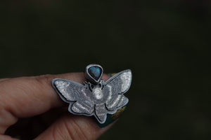 a person is holding a ring with a butterfly on it
