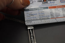 a person holding a piece of metal near a ruler