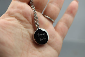 a person holding a black and silver necklace