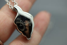 a close up of a person holding a small necklace