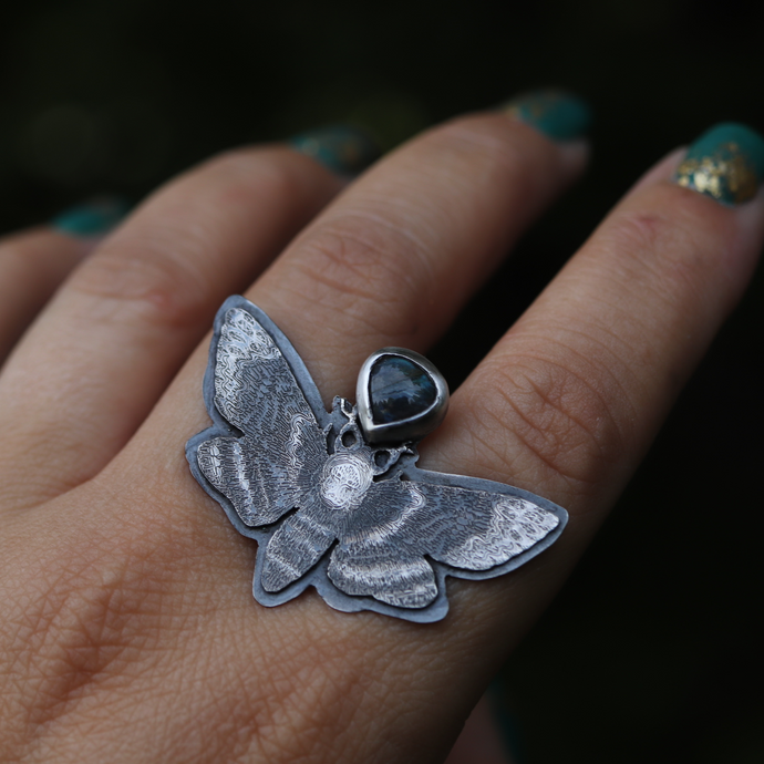 a woman's hand with a butterfly ring on it