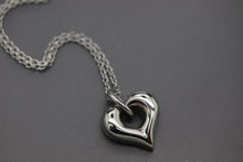 a silver heart shaped pendant on a chain