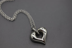 a silver heart shaped pendant on a chain