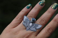 a woman's hand with a butterfly ring on it